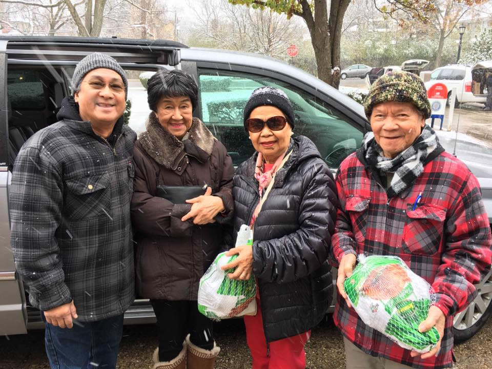 four people in winter coats holding turkeys